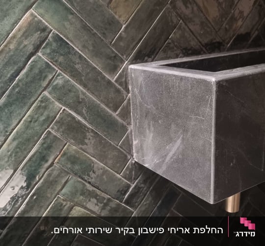 כיור אבן וברז זהב על רקע אריחים ירוקים